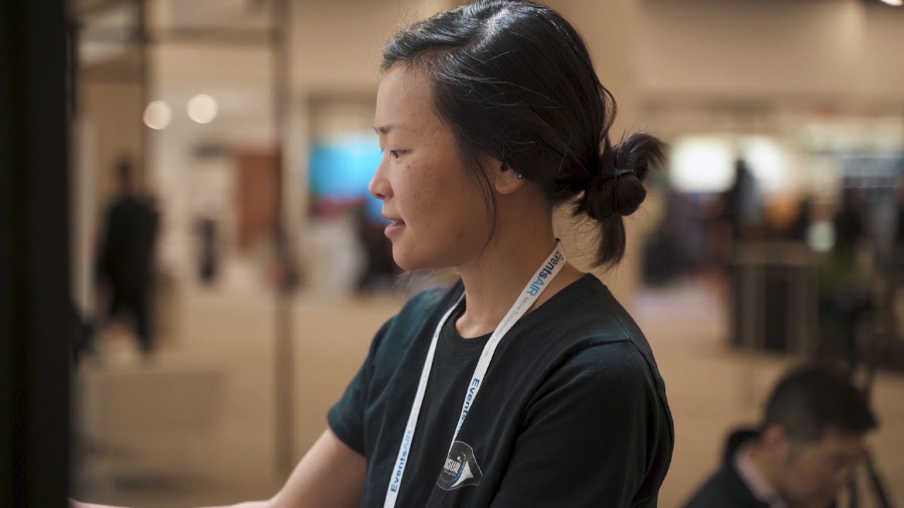 Woman engaged in visual storytelling at an exhibition booth, showcasing creativity and audience engagement at a conference.