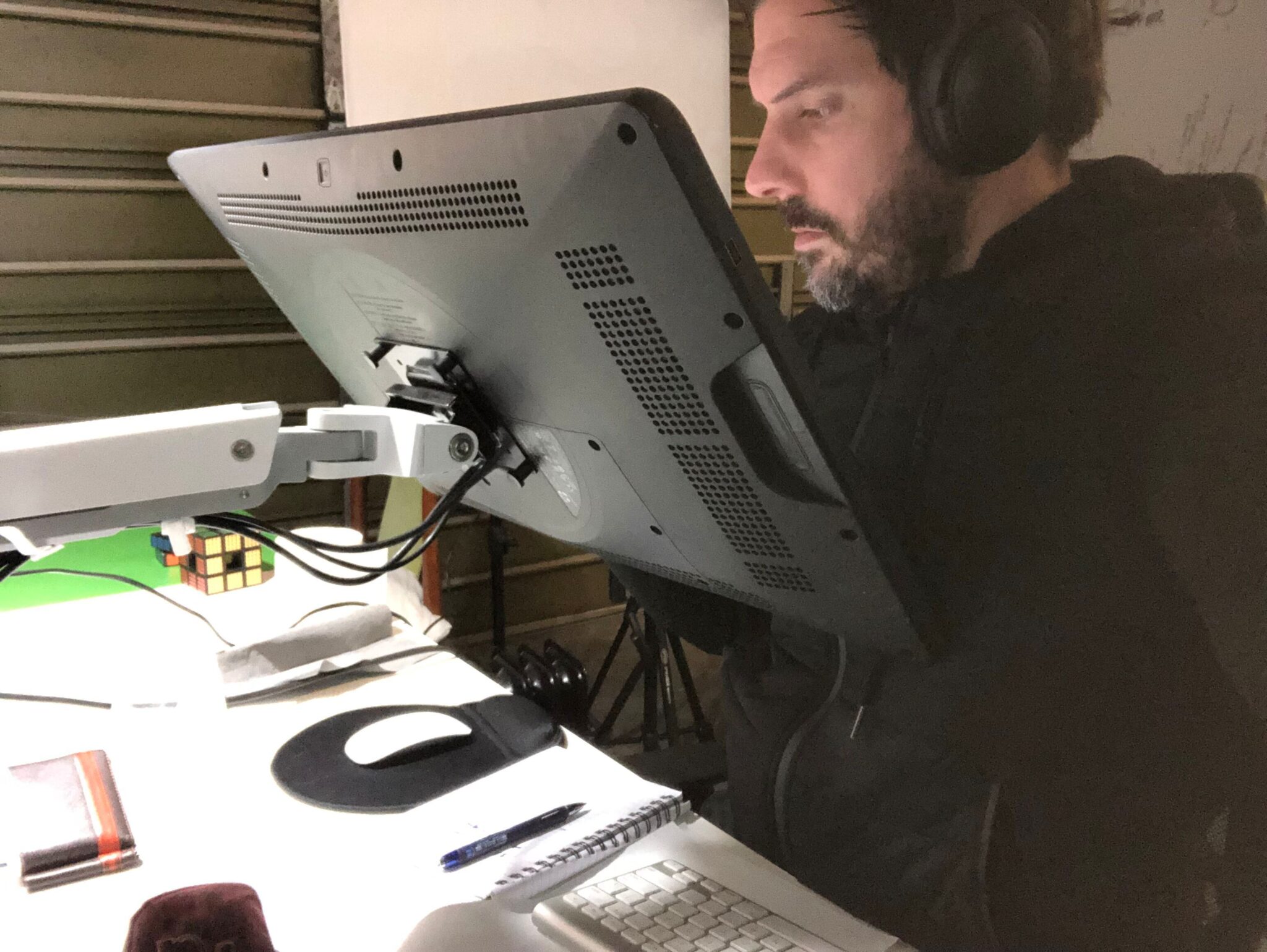 A bearded man wearing headphones is focused on a mounted screen